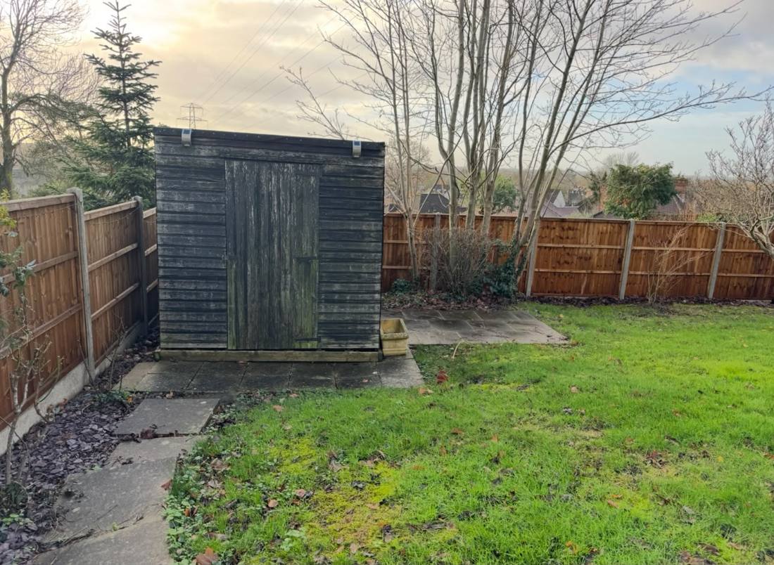 The garden before: an old timber shed on a sloping lawn
